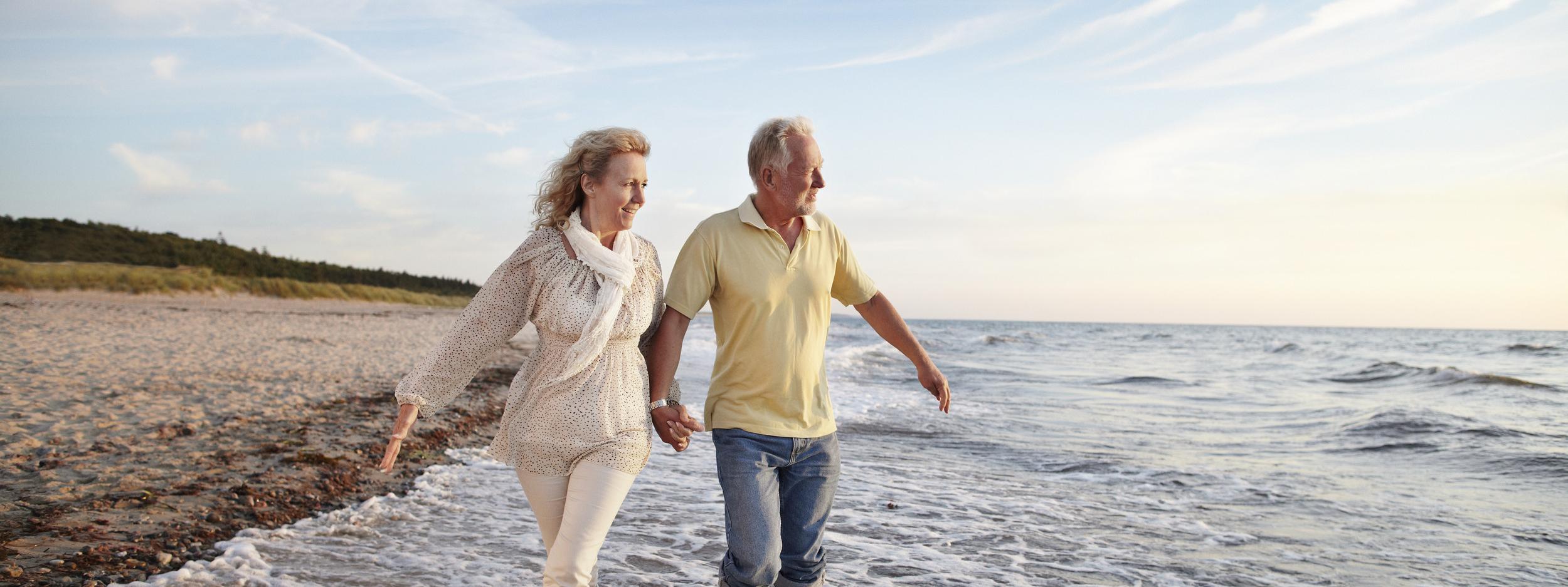 Mature couple paddling in sea looking at sunset