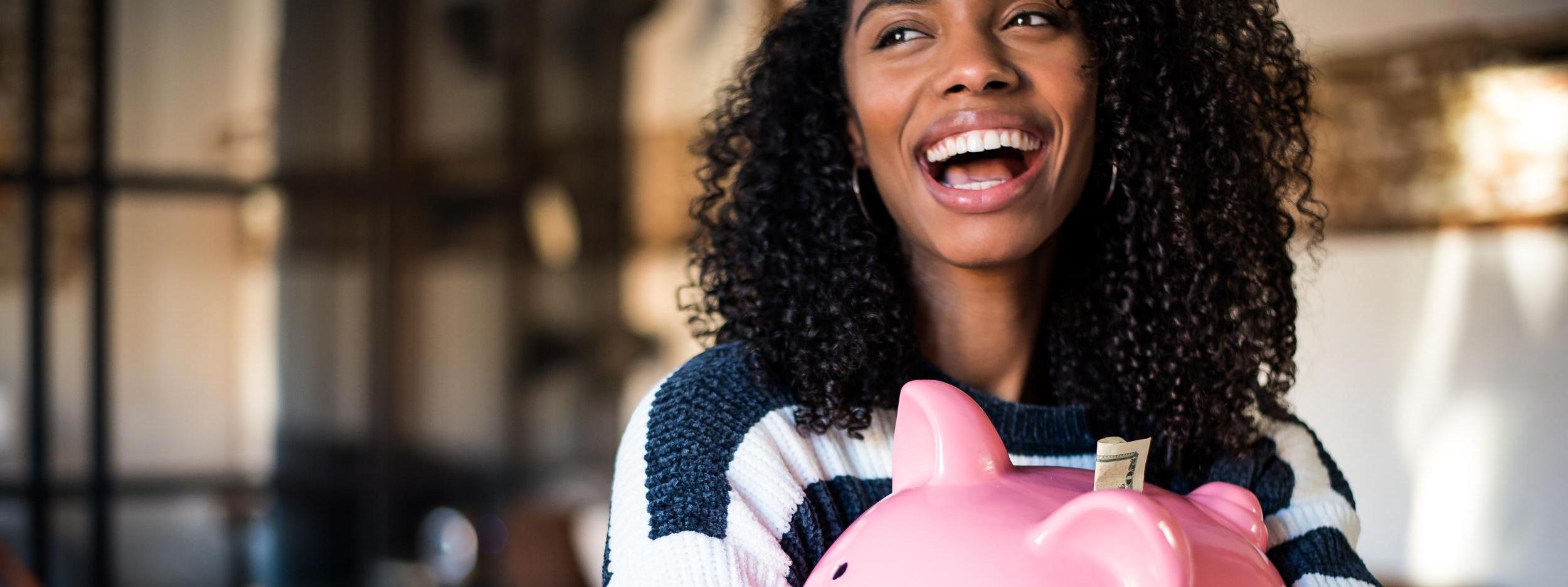 Black woman hugging her piggy bank